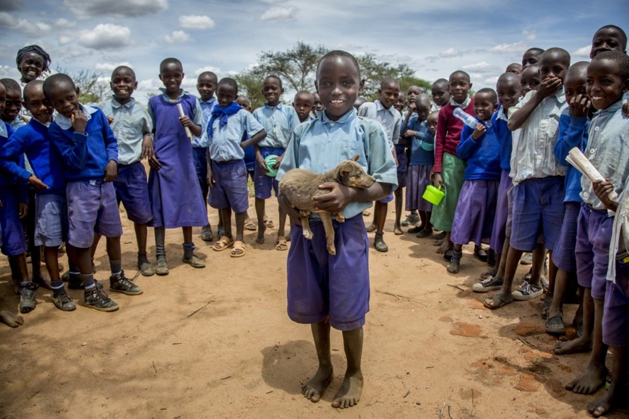 eight year old Kimuli Mbondo holds three month old Simba who has been vaccinated