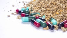 Stock image of animal feed and pill capsules, antibiotics in livestock feed concept.